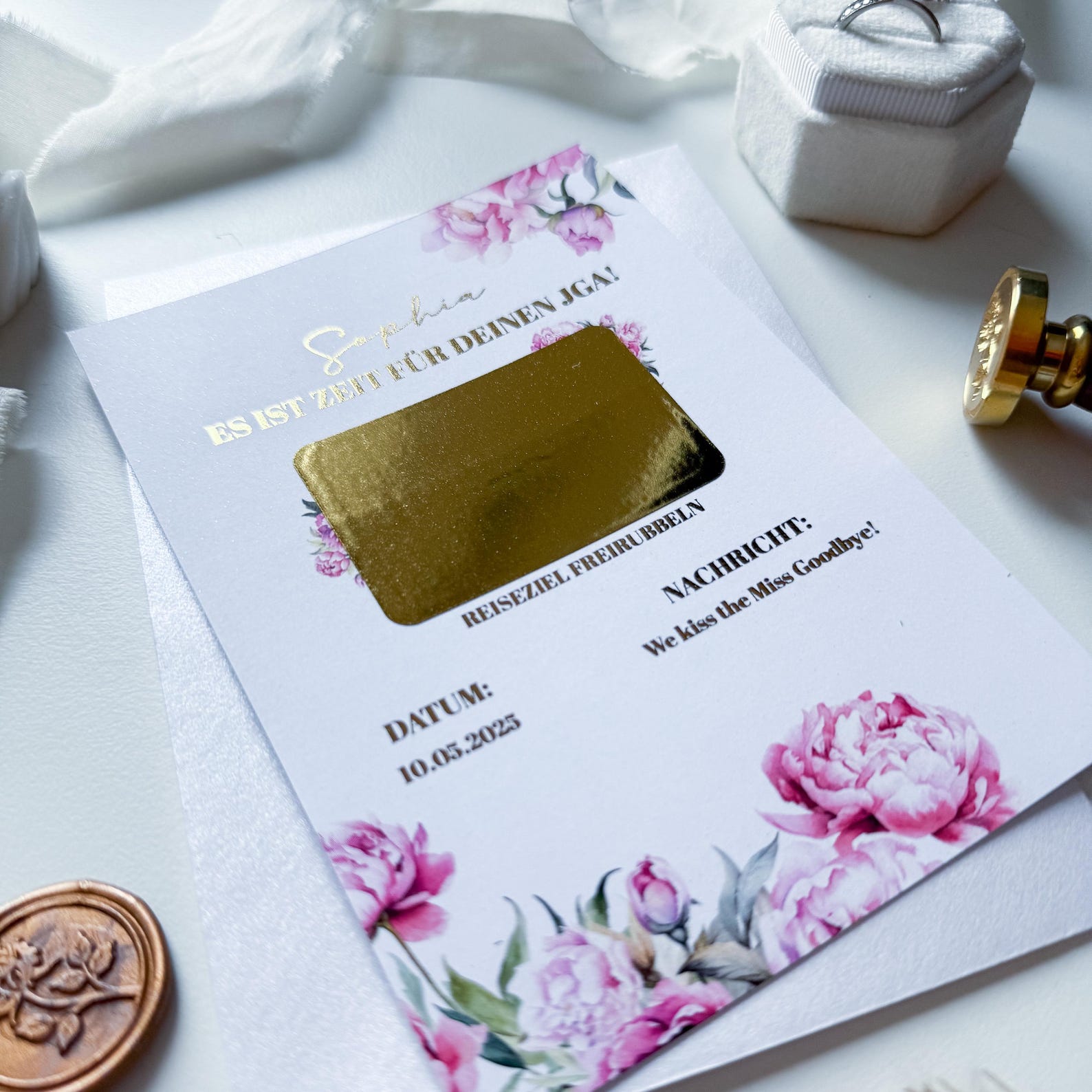Der funkenschauer JGA Gutschein „Reisegutschein verschenken“ im Pfingstrosenzauber-Design: Rubbelkarte A6 mit pinken Blumen, goldenem Rubbelfeld, deutschem Text; auf weißem Hintergrund mit Wachssiegel und Band. Datum „10.05.2023“ sichtbar.