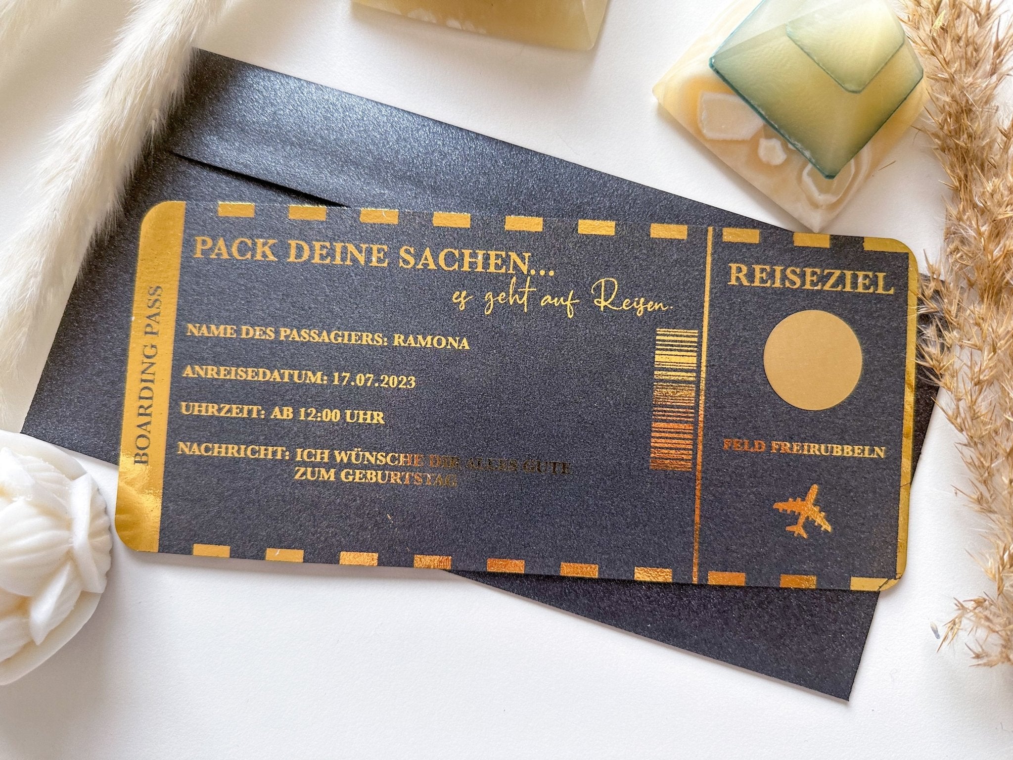 Ein gold-schwarzer Reisegutschein von Funkenschauer mit deutschem Text, personalisiert für „Ramona“ und Abreise am 17.07.2023 nach „Feld Freirubelen.“ Das perfekte Geschenk für Reiseliebhaber, stilvoll auf weißem Untergrund inszeniert.