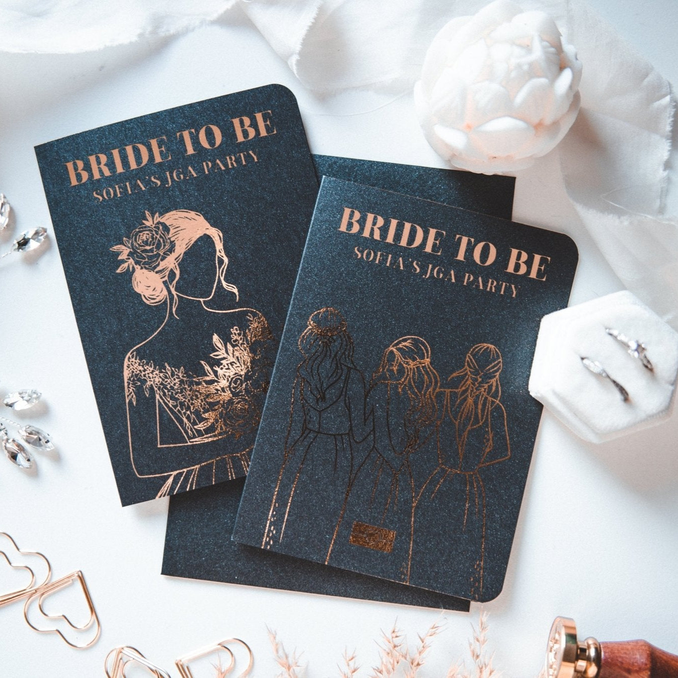 Sofias Junggesellinnenabschied besteht aus zwei schwarzen „BRIDE TO BE“-Karten von funkenschauer, personalisiert mit Frauenillustrationen in Goldfolie und gepaart mit dekorativen weißen Blumen, Schmuck und einem Stift.
