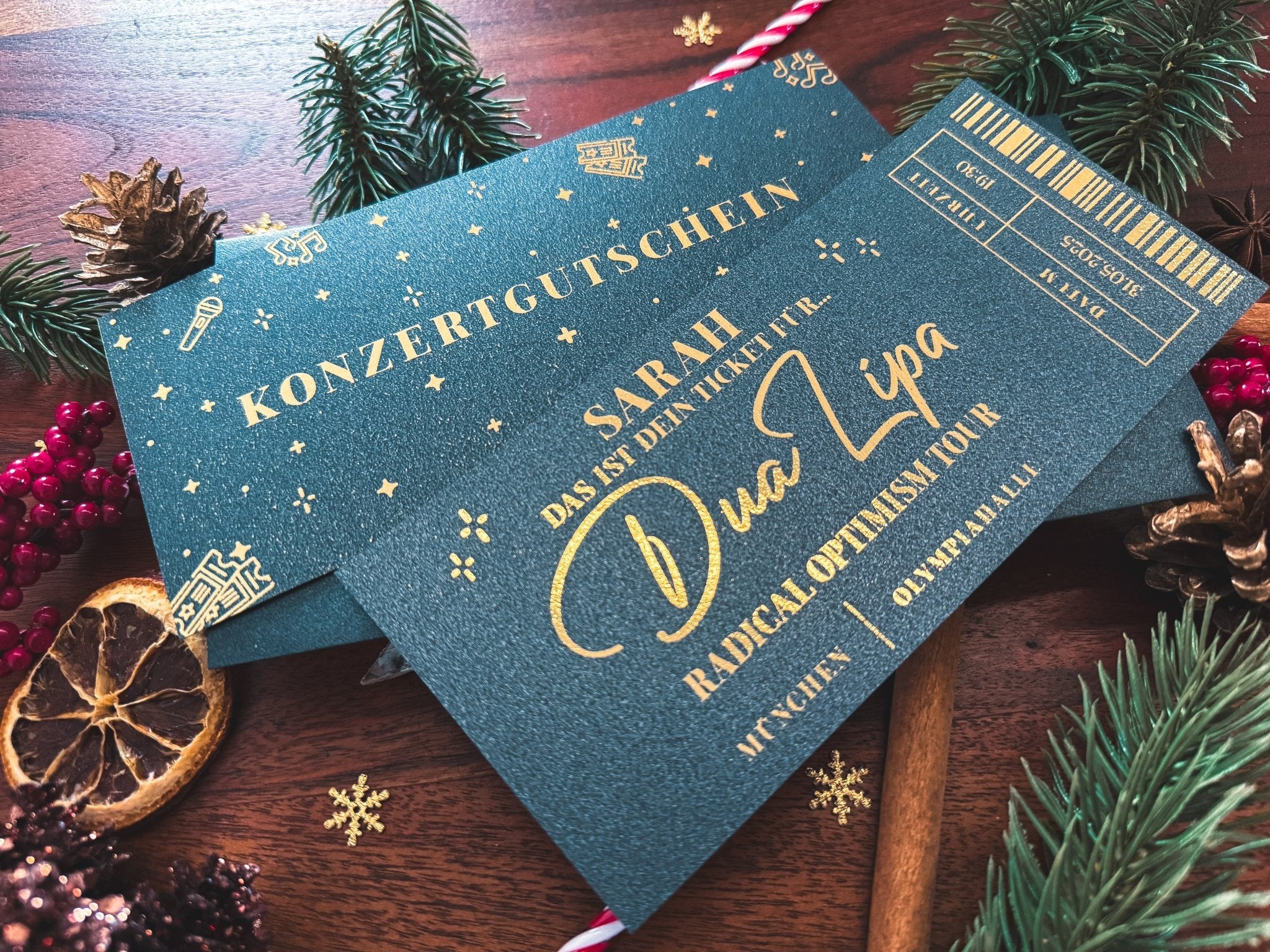 Ein Konzertgutschein Personalisiert von funkenschauer für Dua Lipa, Coldplay oder Ed Sheeran liegt festlich dekoriert - das perfekte Weihnachtsgeschenk und Konzertticket für Musikfans.