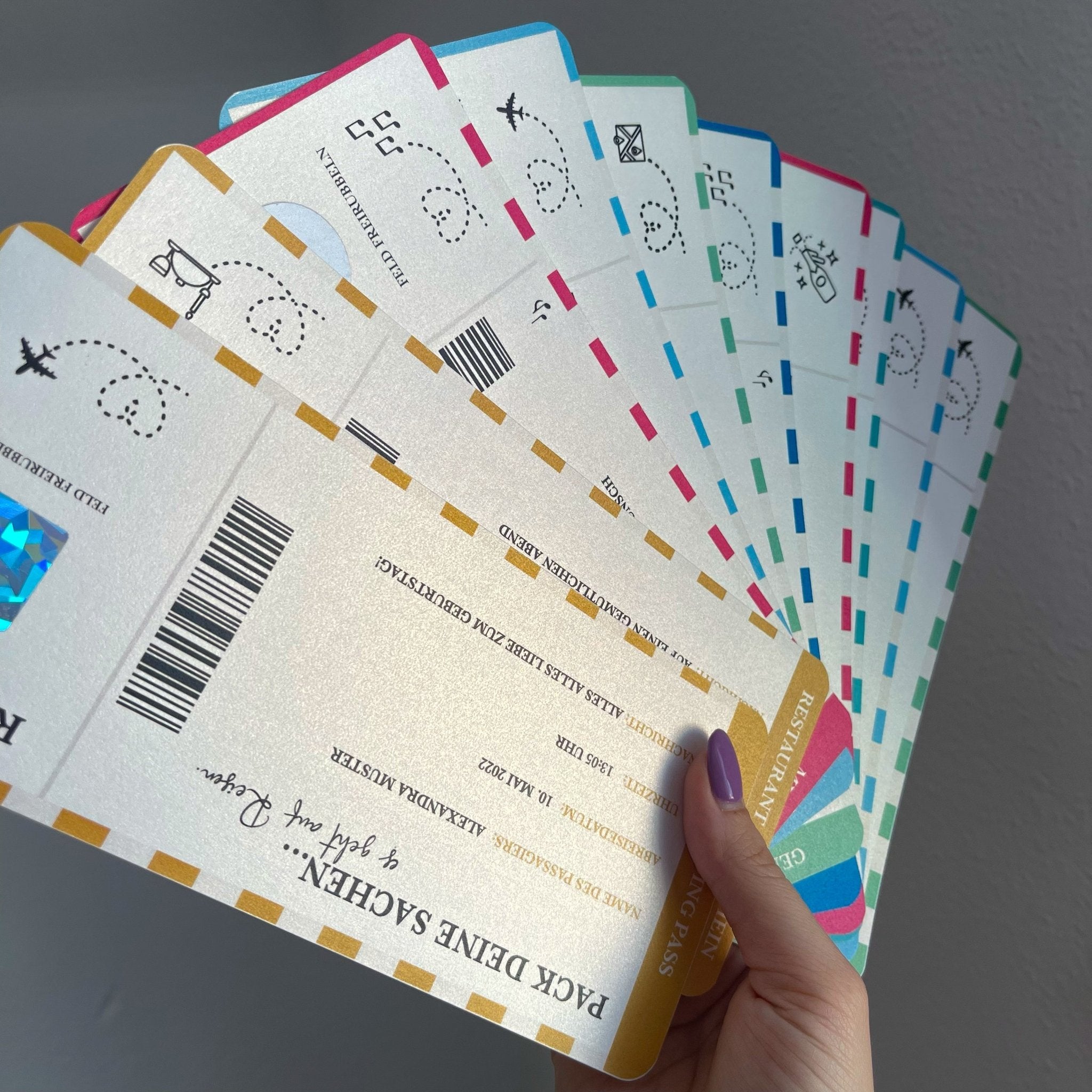 Eine Hand zeigt leuchtende „Reisegutscheine zum Verschenken“ von funkenschauer, die an Flugtickets mit Codes, Barcodes und Motiven erinnern. Die violetten Nägel der Person bilden einen schönen Kontrast zu den Tickets und schaffen so einen perfekten Schnappschuss für jeden Reiseliebhaber.