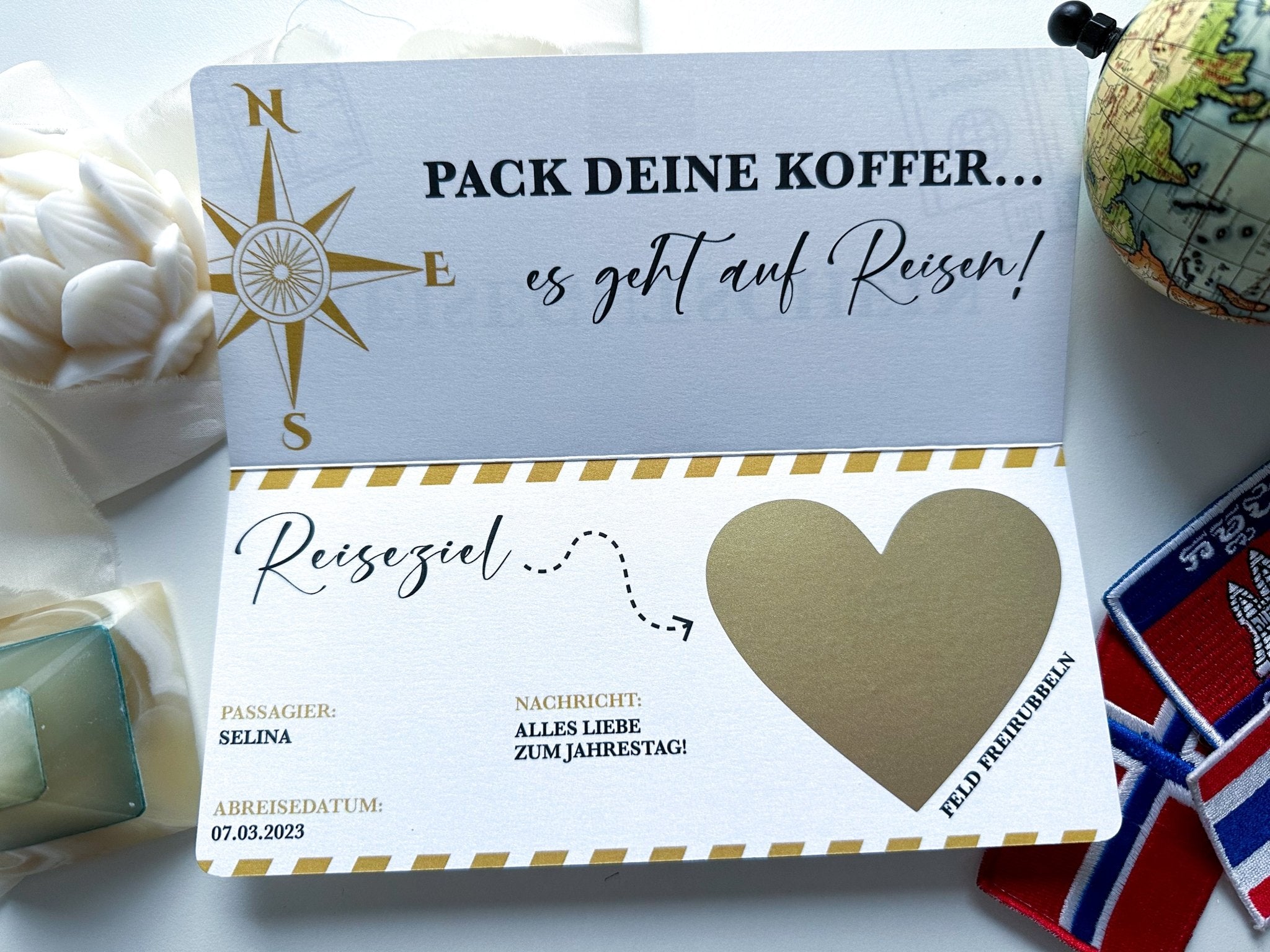 Der „Reisegutschein zum verschenken“ von Funkenschauer ist eine Reisekarte mit Weltkartenmotiv und Kompass-Design mit dem Text „PACK DEINE KOFFER... es geht auf Reisen!“ Es enthält ein „Reiseziel“-Herz für Selina und die Aufschrift „ALLES LIEBE ZUM JAHRESTAG!“ mit Reisedatum 07.03.2023.