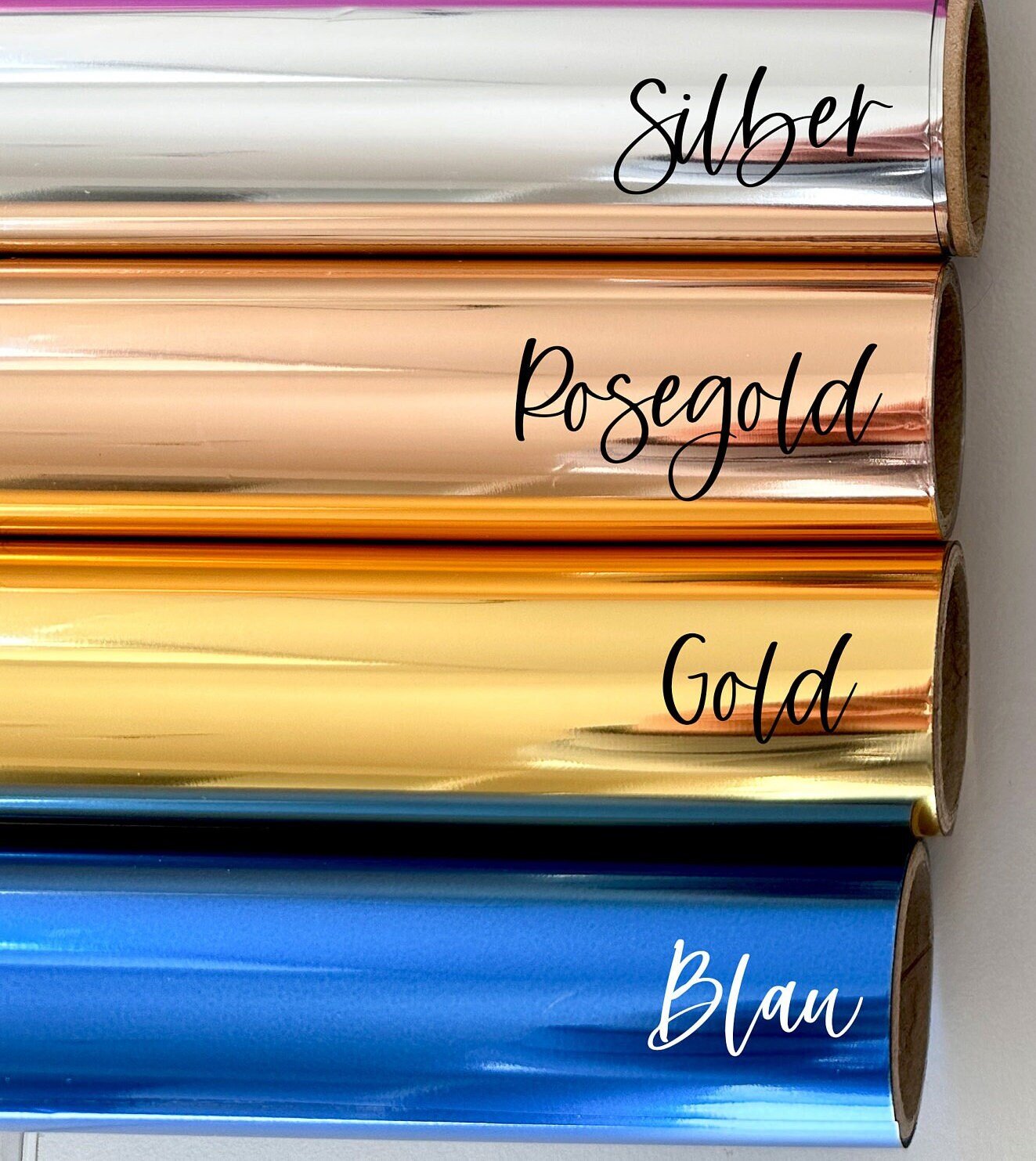 Vier Rollen glänzendes metallisches Vinyl sind horizontal gestapelt und von oben nach unten mit Silber (Silber), Rosegold (Roségold), Gold und Blau (Blau) beschriftet. Ihr exklusives Design eignet sich ideal zum Gestalten eines personalisierten Reisepasses als Reisegutschein von Funkenschauer.