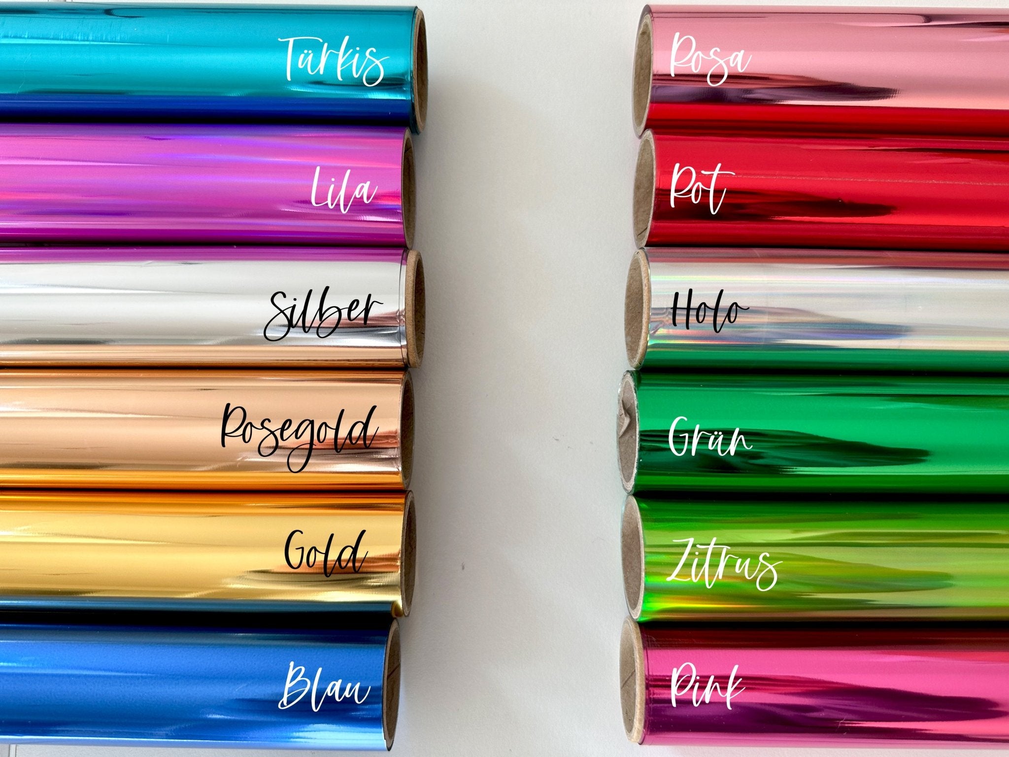 Zwölf Rollen holografischer Folie bilden eine farbenfrohe Palette für Rubbelkarten-Fans. Die auf Deutsch beschrifteten Farben – Türkis, Lila, Silber, Roségold und mehr – eignen sich perfekt für die Gestaltung funkenschauers Zeit statt Zeug Gutschein-Geschenke, die in jeder Farbe glänzen.