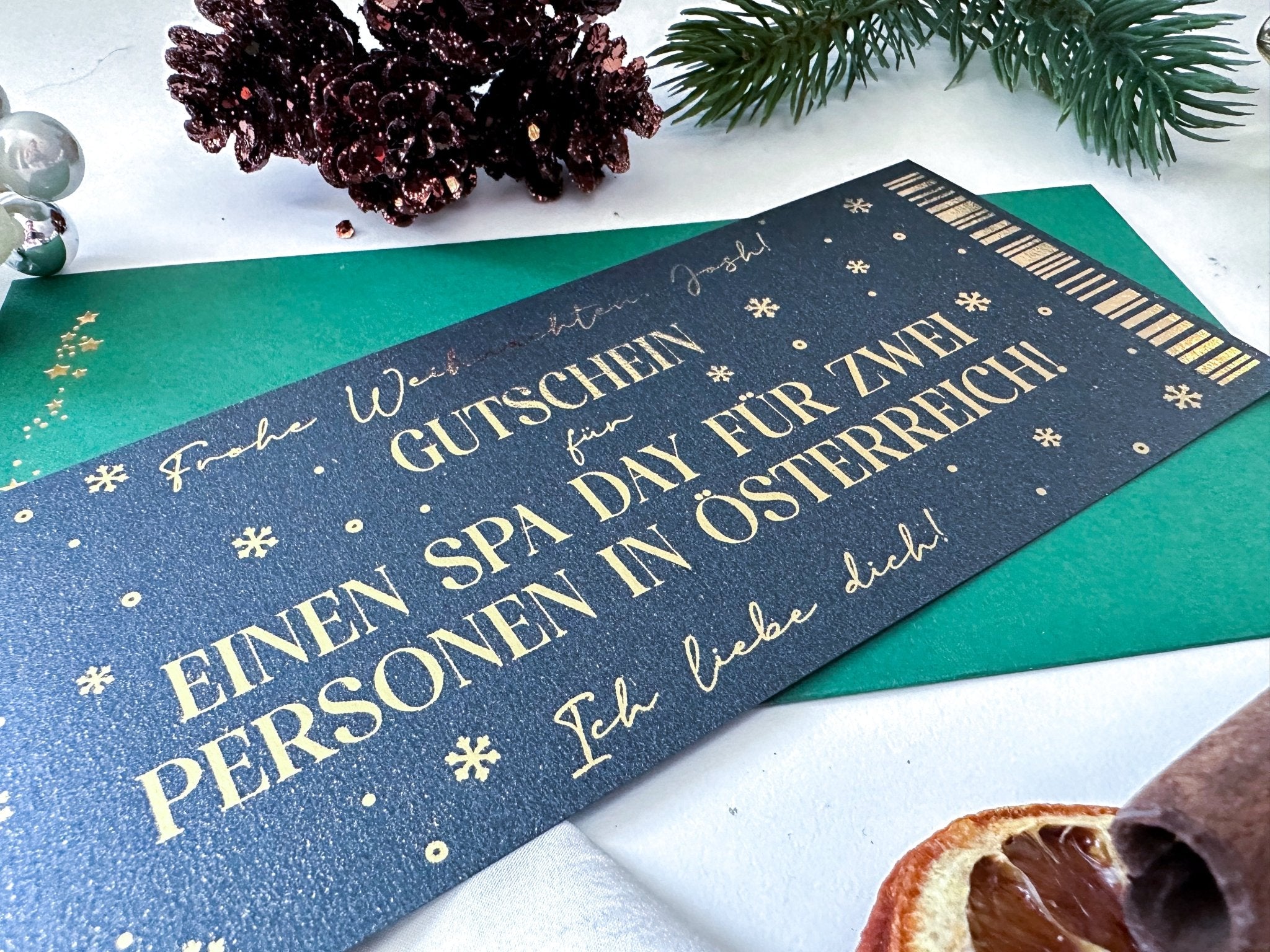 Eine Nahaufnahme der funkenschauer EXKLUSIVE WEIHNACHTSGESCHENKE Black Edition - ein personalisierter Weihnachtsgutschein als Gutscheinkarte auf grΓΌnem Umschlag mit festlicher Deko. Das perfekte, besondere Geschenk fΓΌr kreative Weihnachten!.
