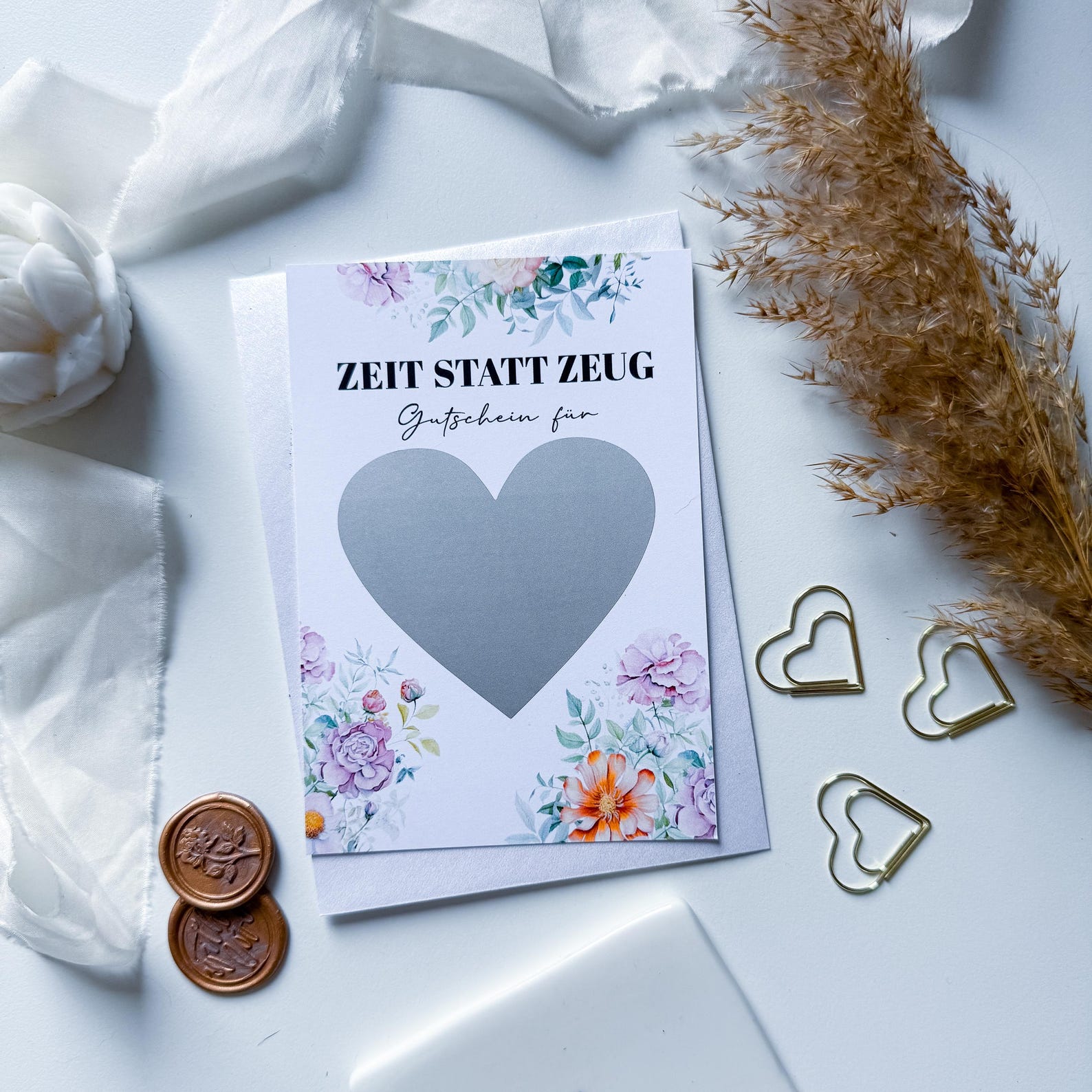 The funkenschauer Zeit statt Zeug Gutschein – personalisierte A6 Rubbelkarte zeigt florale Motive, ein silbernes Herz, weiße Stoffdetails, Trockenblumen und goldene Herz-Clips. Mit „ZEIT STATT ZEUG“-Schriftzug. Individuell für jeden Anlass gestaltbar.