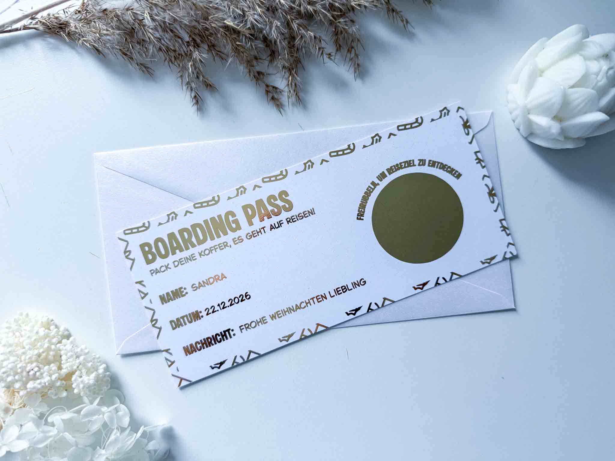Die funkenschauer Karte Weihnachten Gutschein Reise personalisiert ist eine Rubbelkarte zum Thema Bordkarte mit deutschem Text und einem Rubbelfeld - ideal als Reisegutschein Weihnachten. Sie ist auf einem weißen Umschlag abgebildet und von weißen Blumen und Pflanzen umgeben.