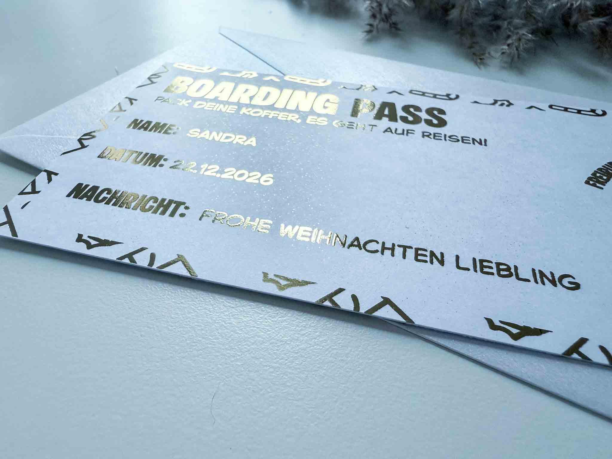 Eine Nahaufnahme der funkenschauer "Karte Weihnachten Gutschein Reise personalisiert" Rubbelkarte zeigt goldenen deutschen Text, adressiert an Sandra für den 22.12.2026, mit "Frohe Weihnachten Liebling" - das perfekte personalisierte Reisegutschein Weihnachten Geschenk!.