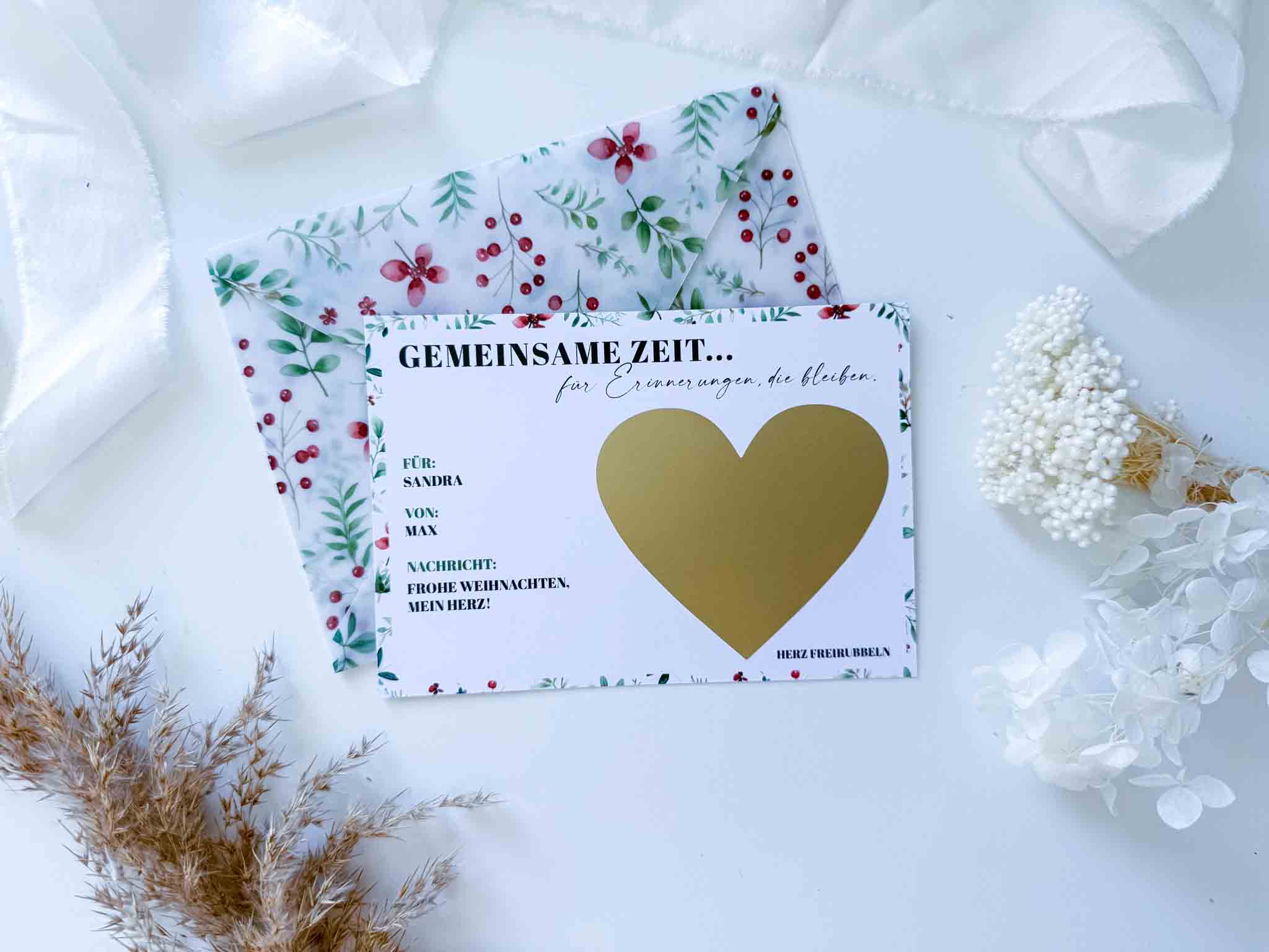 Die funkenschauer "Weihnachten Gutschein Zeit statt Zeug" Weihnachtskarte mit handgemachtem Umschlag liegt auf weißem Stoff, umgeben von Trockenblumen - ideal als Gutschein zu Weihnachten oder besondere Rubbelkarte.