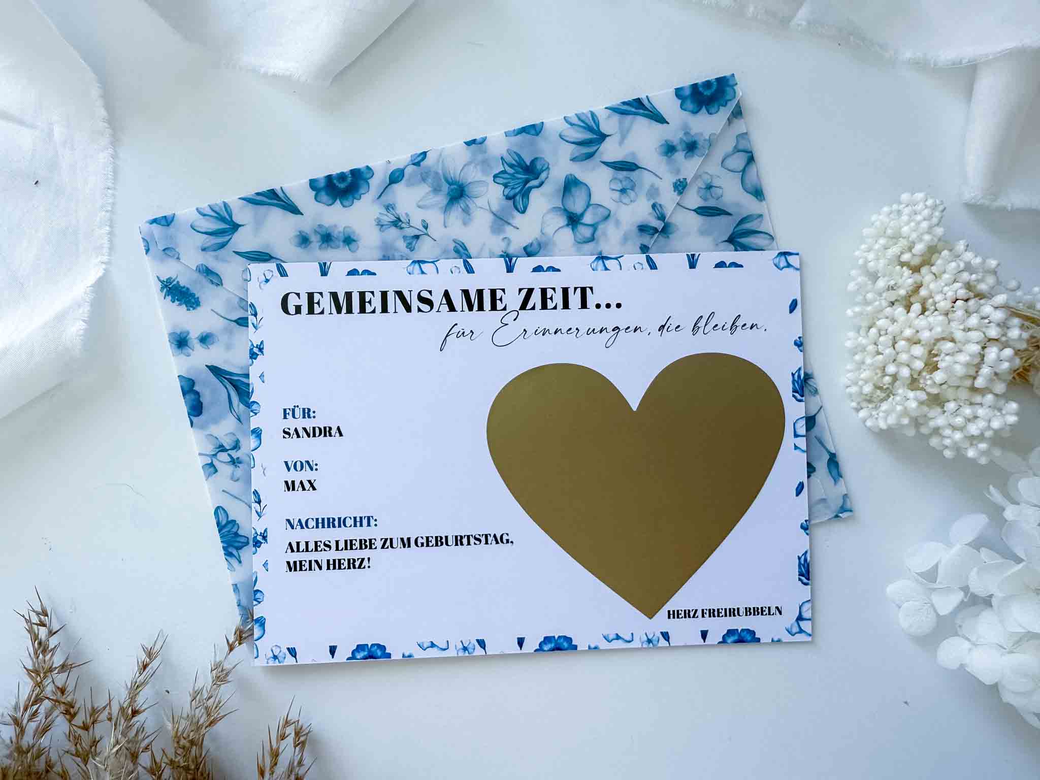 Der Gutschein Zeit statt Zeug + handgemachter Umschlag von funkenschauer ist ein personalisiertes A6-Rubbelkarten-Geschenk mit Goldherz, deutscher Grußkarte, handgeschriebener Botschaft und elegantem Blumenarrangement.