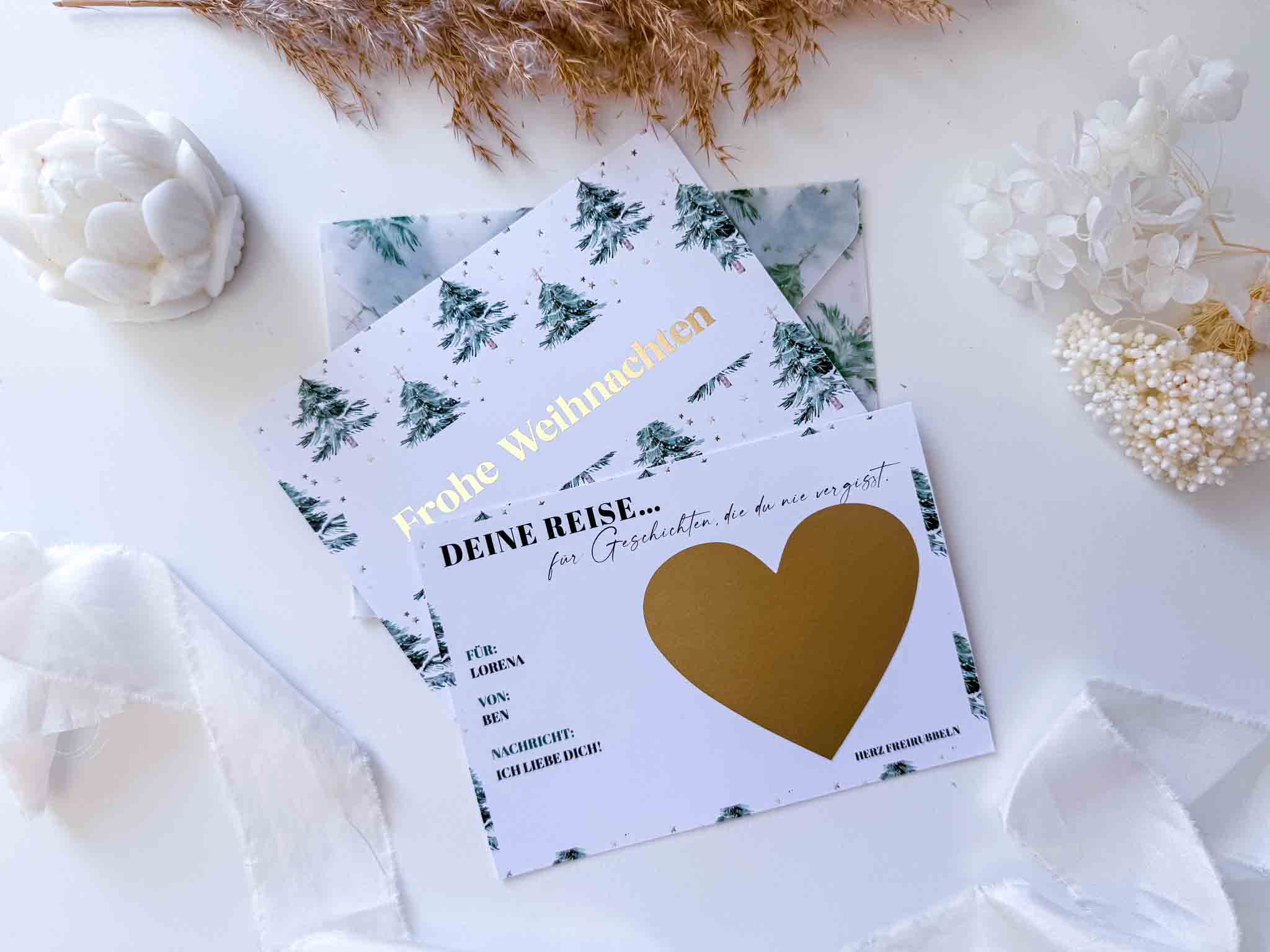 Zwei festliche Karten von funkenschauer: eine sagt "Frohe Weihnachten" mit Bäumen, die andere ist eine Rubbelkarte "Reisegutschein Weihnachten" mit goldenem Herz - perfekt personalisierte Weihnachtsgeschenke!.