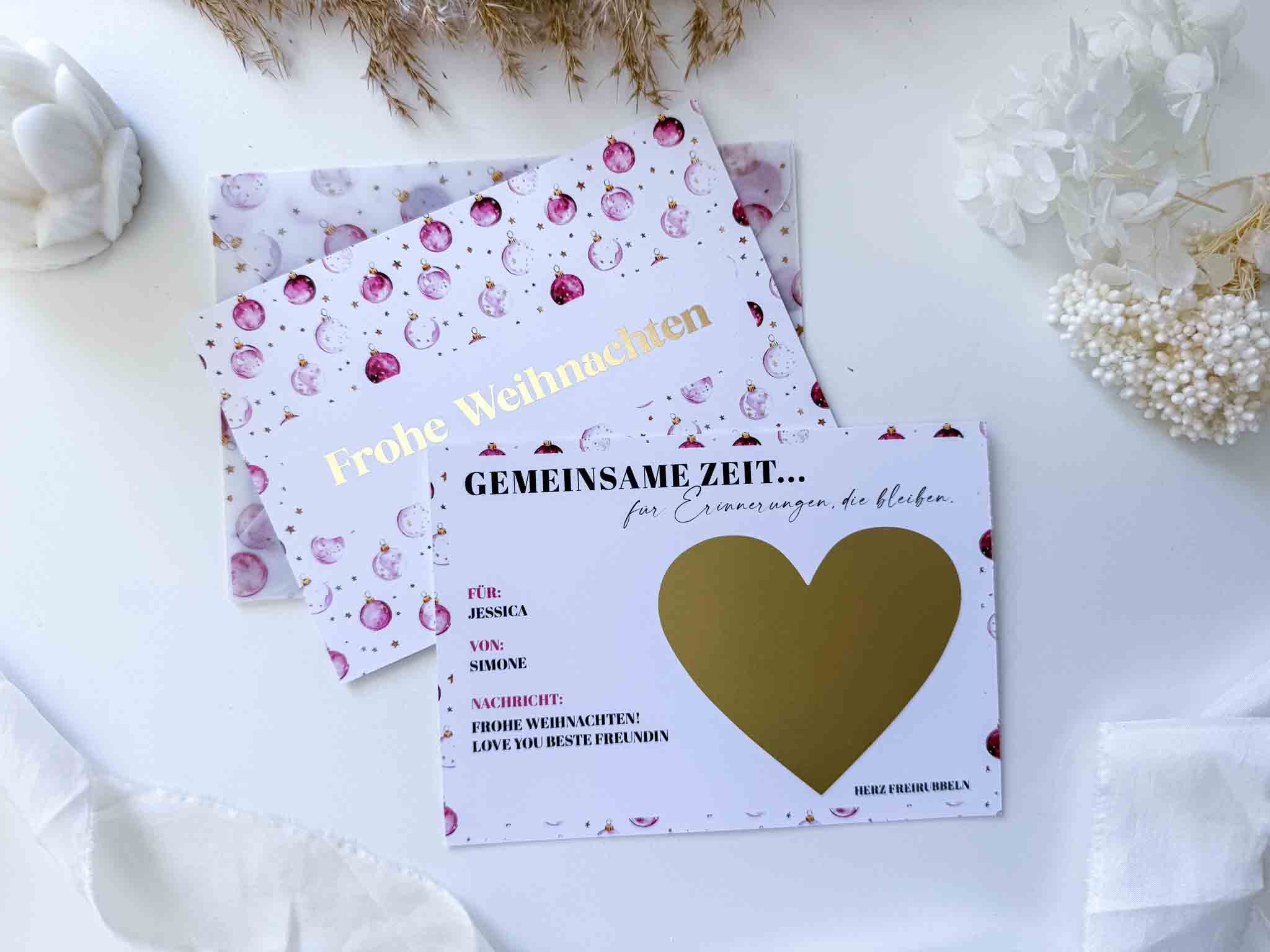 Zwei Weihnachtsgutschein Zeit statt Zeug Karten von funkenschauer sind auf weiß mit getrockneten Blumen dargestellt. Auf der einen steht "Frohe Weihnachten", die andere hat ein Rubbelherz für Ihre Nachricht oder Ihren Gutschein, beide mit rosa Ornamenten für eine festliche Note.