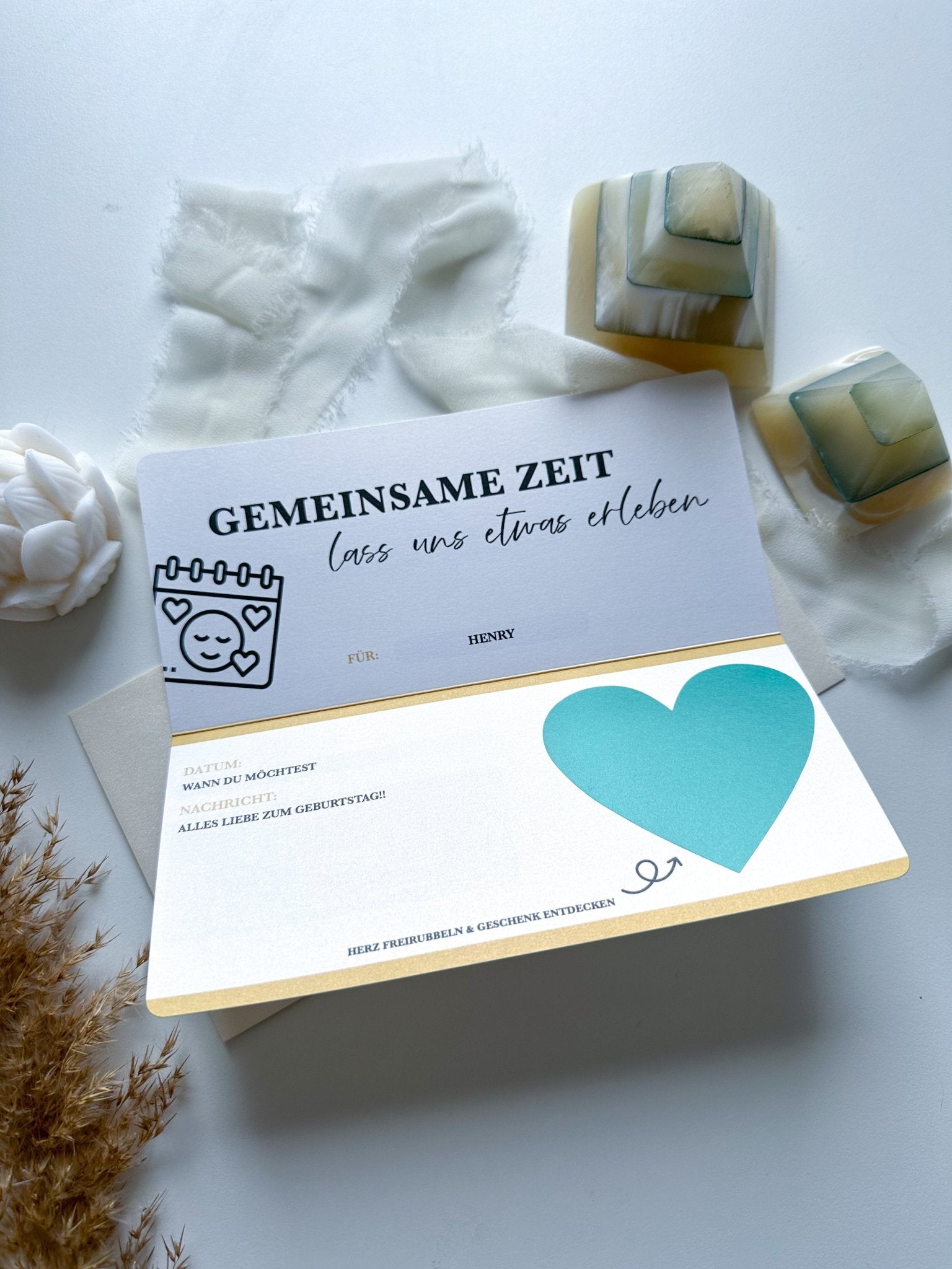 Ein Funkenschauer-Gutschein Zeit statt Zeug liegt offen auf einem Tisch mit blauem Herzmotiv und der Aufschrift „GEMEINSAME ZEIT lass uns etwas erleben“ bereit zur Personalisierung. Weiche Stoffe, Steinseifen und Trockenblumen schaffen eine gemütliche Atmosphäre rund um diese anpassbare Karte, die in 17 Farben erhältlich ist.