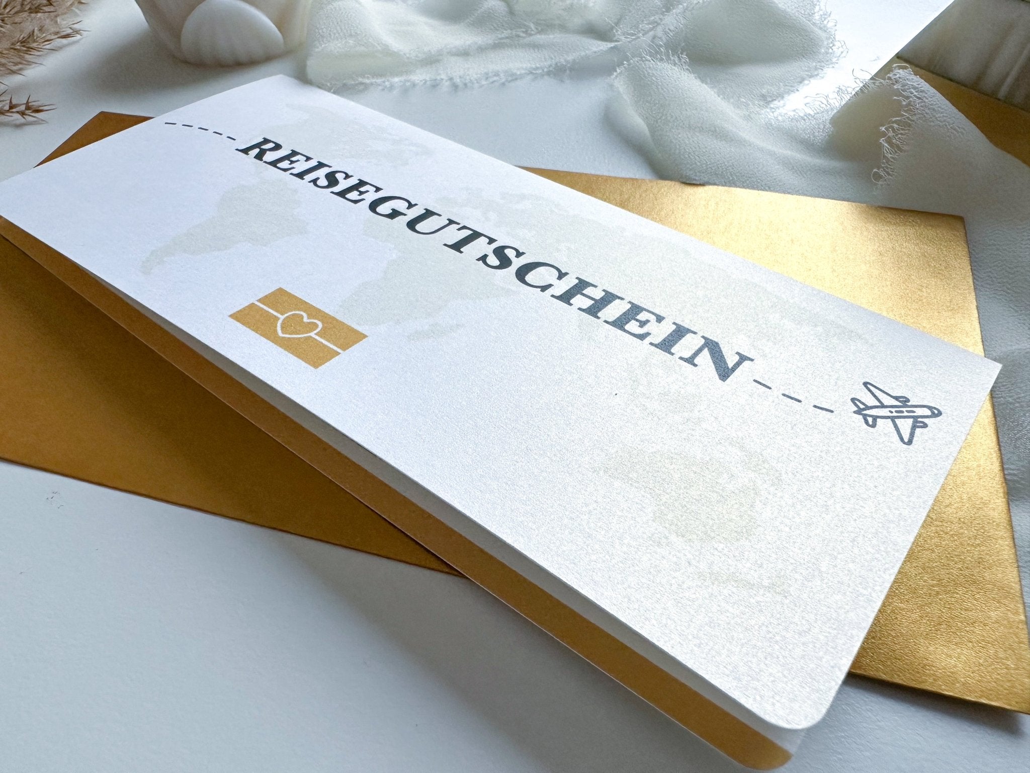 Ein „Reisegutschein Personalisierbar mit Rubbelfeld zum Aufklappen“ von funkenschauer mit der Aufschrift „Reisegutschein“ auf einem goldenen Umschlag. Die Karte im Flugticket-Design zeigt ein kleines Herz-Symbol und ein Flugzeug-Symbol und suggeriert so eine Reise oder einen Ausflug. Im Hintergrund sind weicher weißer Stoff und getrocknete Blumen zu sehen. Dieser personalisierbare Rubbelgutschein ist ein perfektes Geschenk für Reiseliebhaber, insbesondere zu Weihnachten, und ist in 17 Farben erhältlich.